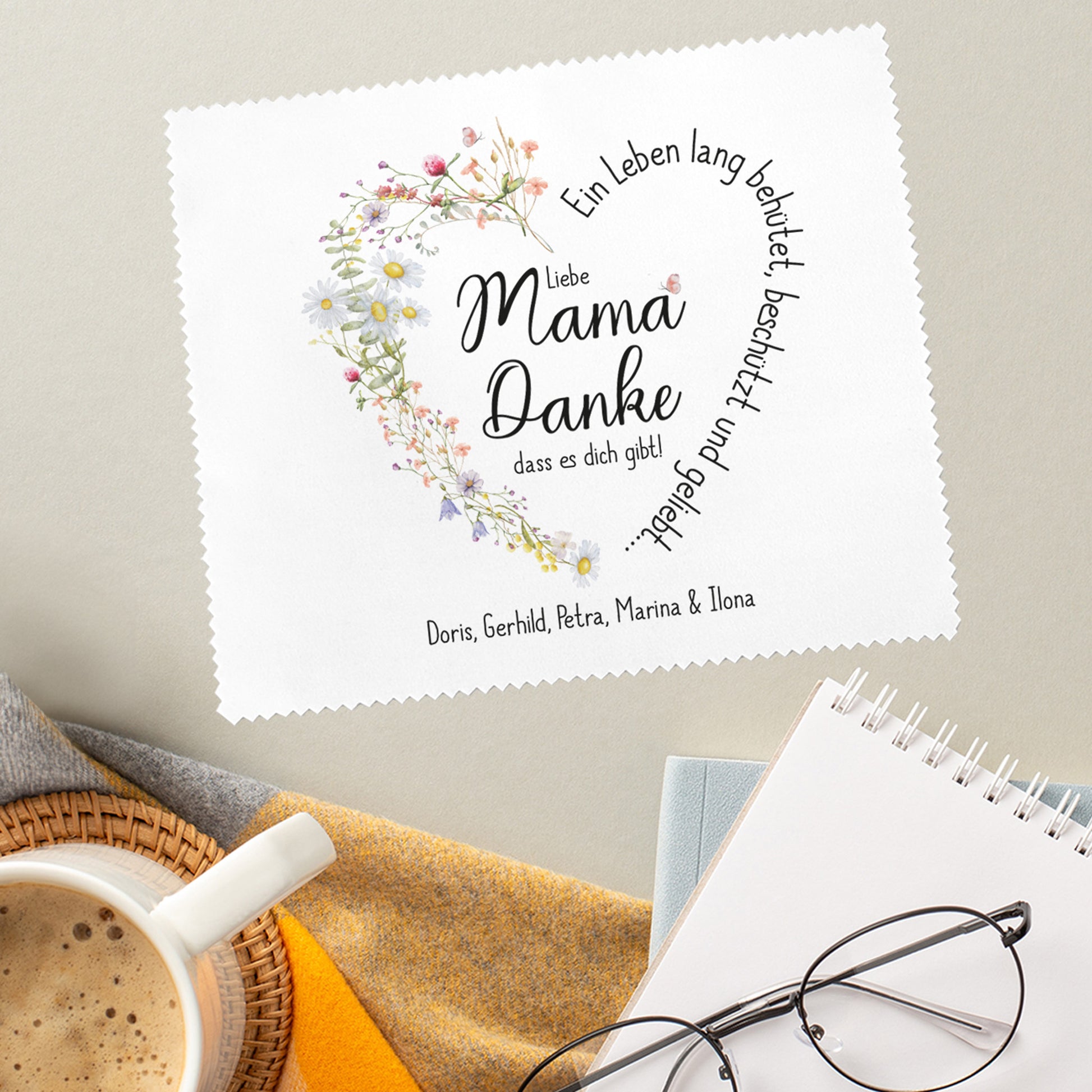 Brillenputztuch mit persönlichem Dankeschön für Mama, stilvoll präsentiert auf einem weichen Untergrund mit Kaffeetasse und Notizblock.