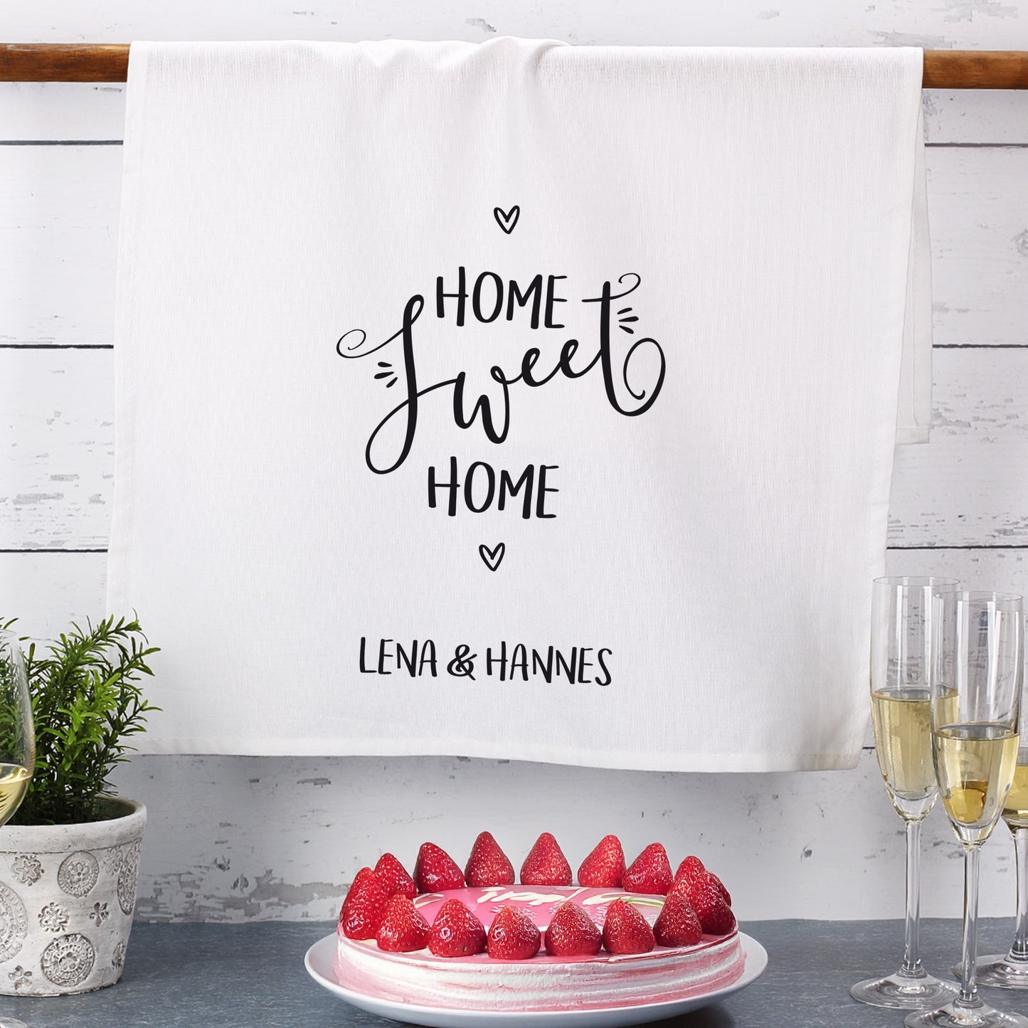 Geschirrtuch mit Namen Lena & Hannes, dekorativ am Regal mit Erdbeerkuchen und Sektgläsern