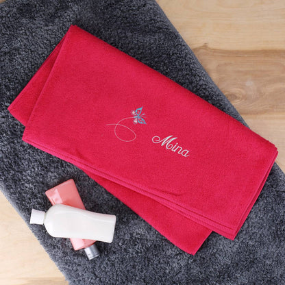 Himbeerfarbenes Badetuch mit Schmetterling und Name bestickt