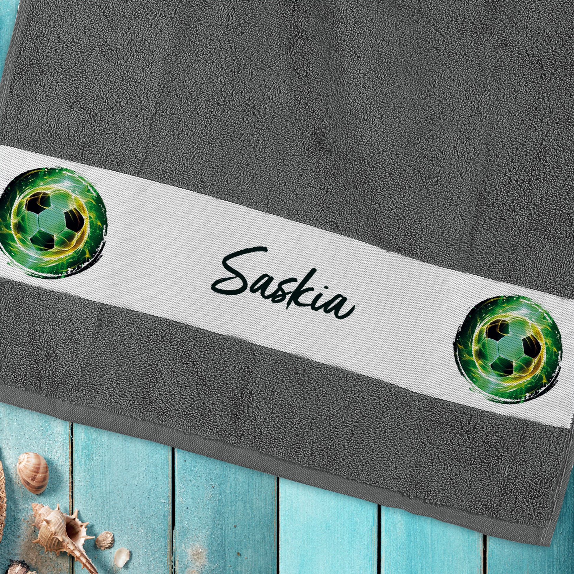 Handtuch mit Fußballmotiv und Namensaufdruck „Saskia“ auf Holzuntergrund