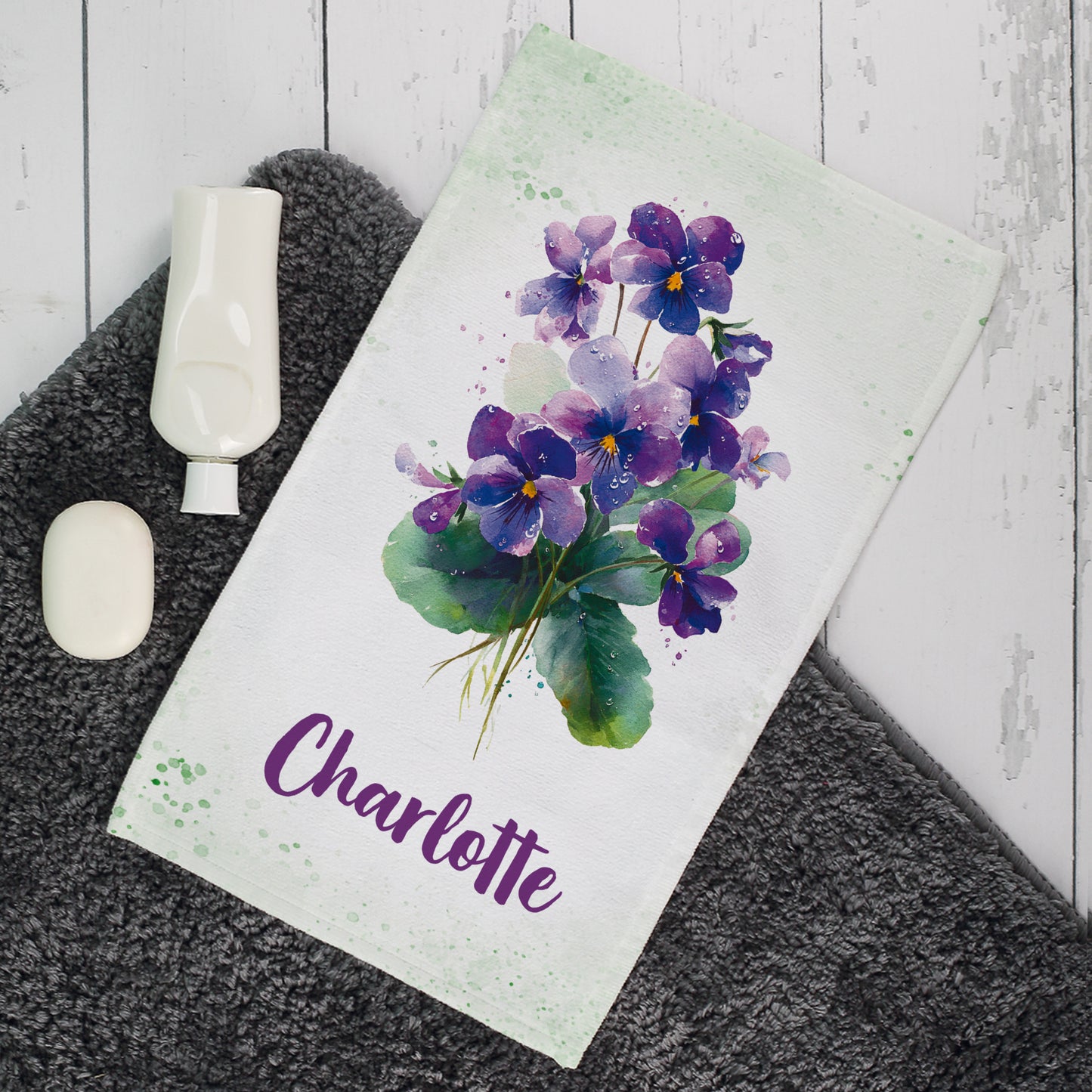 Gästehandtuch mit violettem Veilchen-Motiv und Name Charlotte im Badezimmer