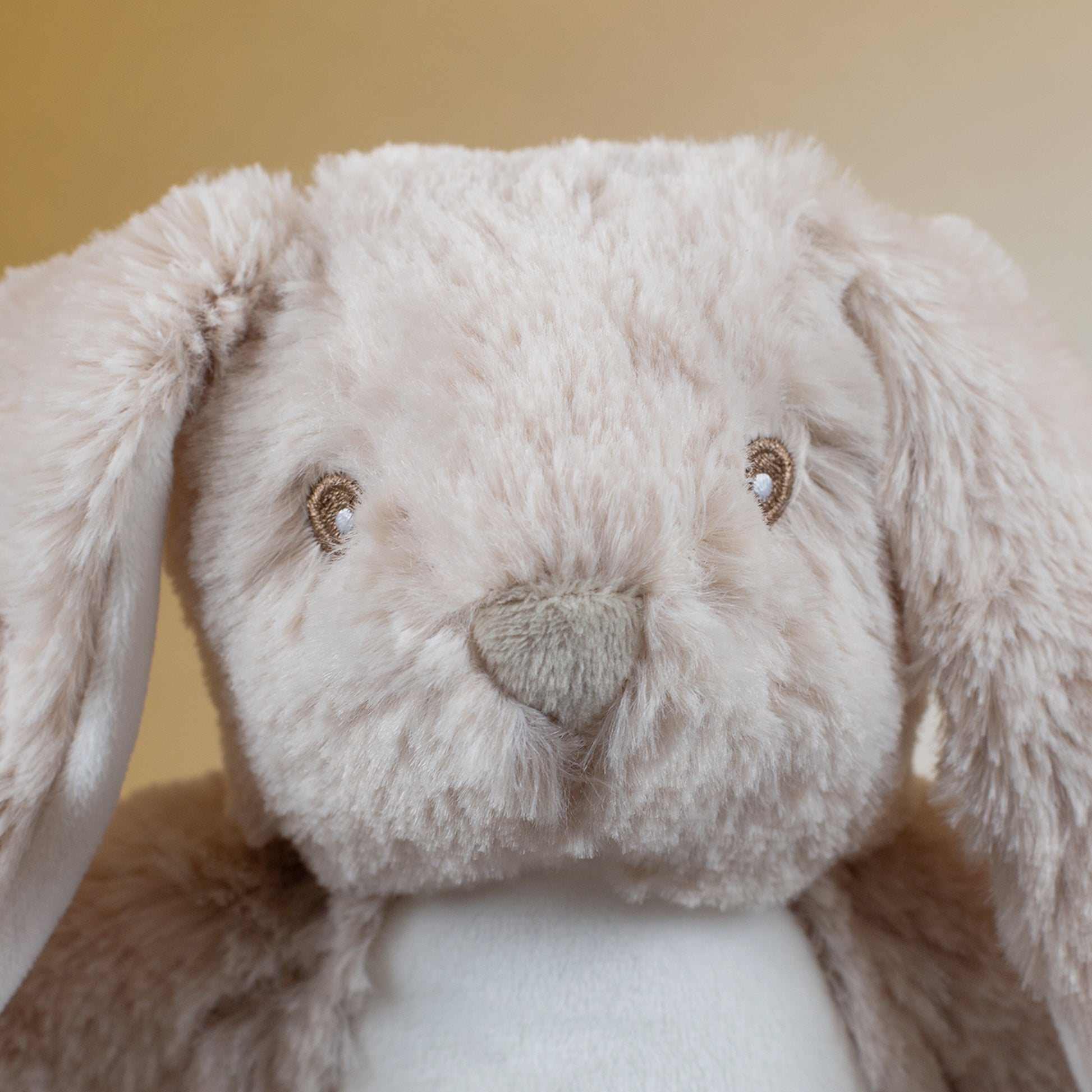 Nahaufnahme des Hasengesichts mit gestickten Augen und kleiner, herzförmiger Nase. Das beigefarbene Fell wirkt besonders weich und flauschig, Details sind deutlich erkennbar.