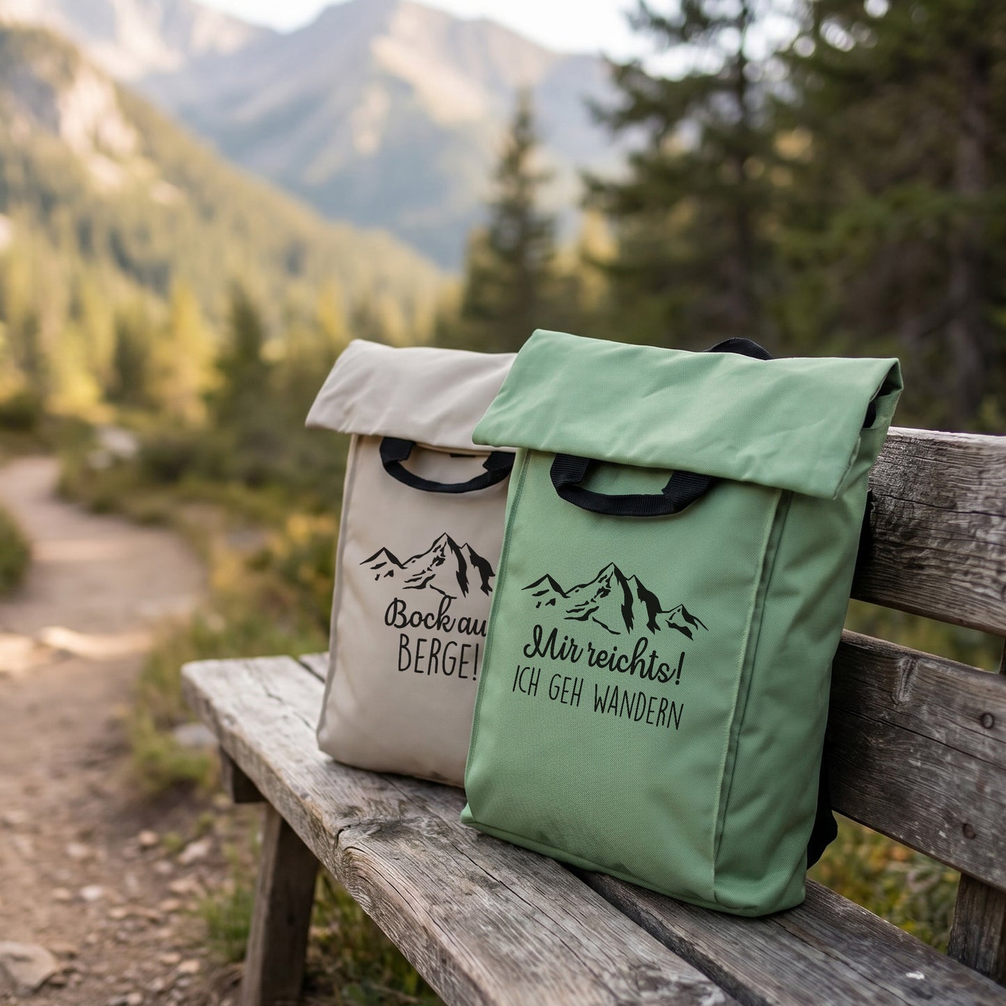 Zwei personalisierte Rucksäcke mit Bergmotiv in Beige und Jadegrün auf einer Holzbank in Berglandschaft