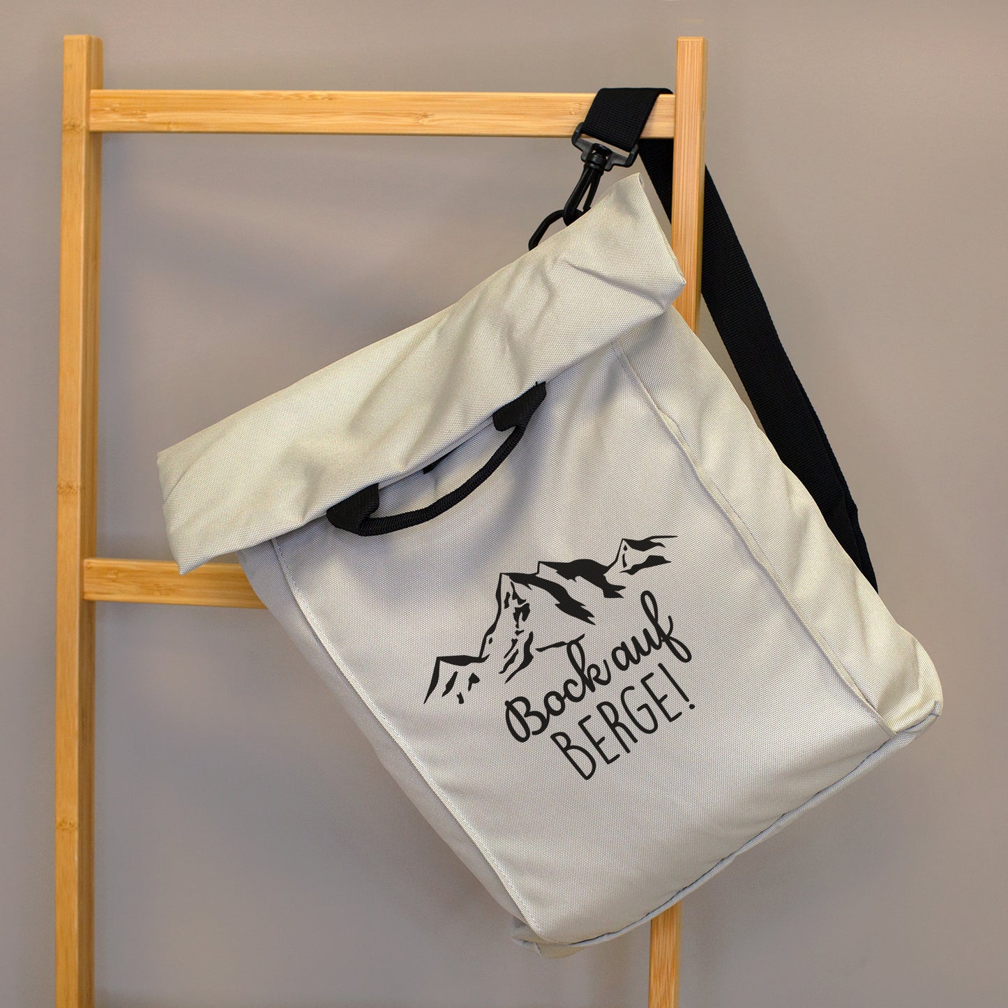 Beiger 2-in-1 Rucksack mit Bergmotiv und Spruch „Bock auf Berge!“ an einer Holzleiter