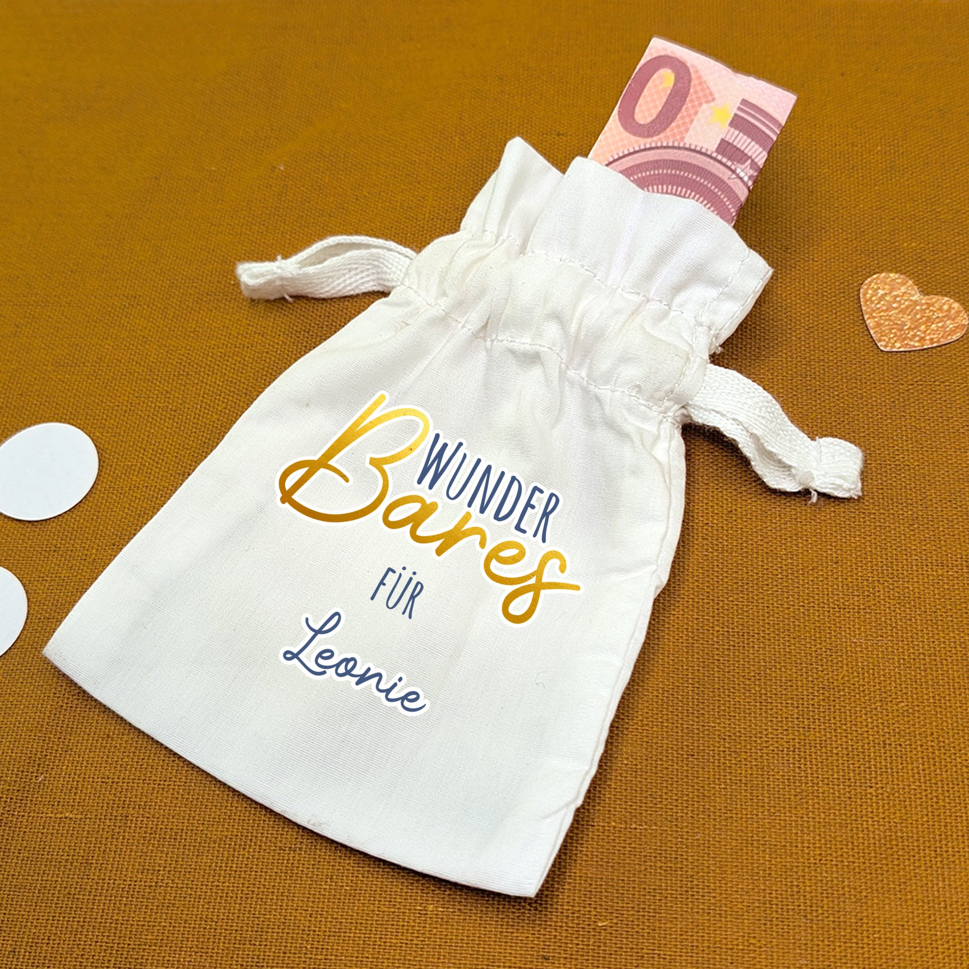 Stoffbeutel mit Aufdruck „WunderBares für Leonie“, daneben Dekoelemente und 10-Euro-Schein