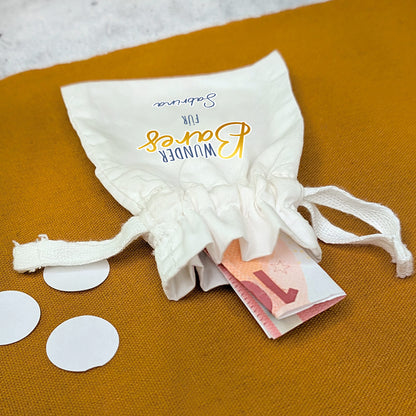 Offenes Säckchen mit Geldschein und sichtbarem Aufdruck „WunderBares für Sabrina“