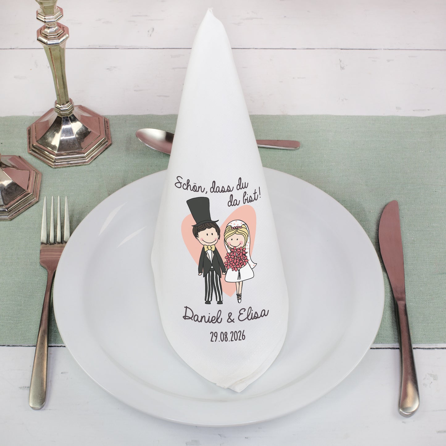 Stoffserviette Hochzeit personalisiert gefaltet auf Teller mit Besteck und Brautpaar Design