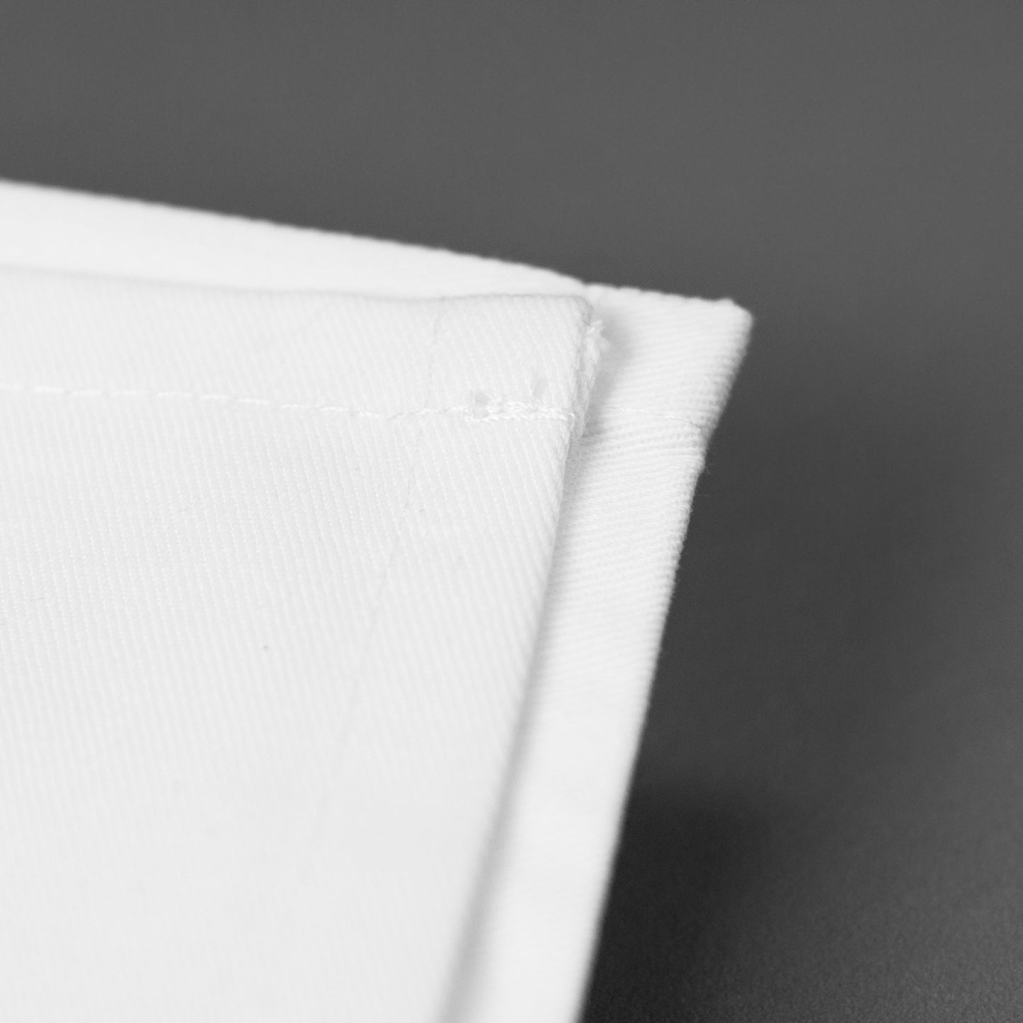 Detailaufnahme der hochwertigen Stoffkante einer weißen Serviette