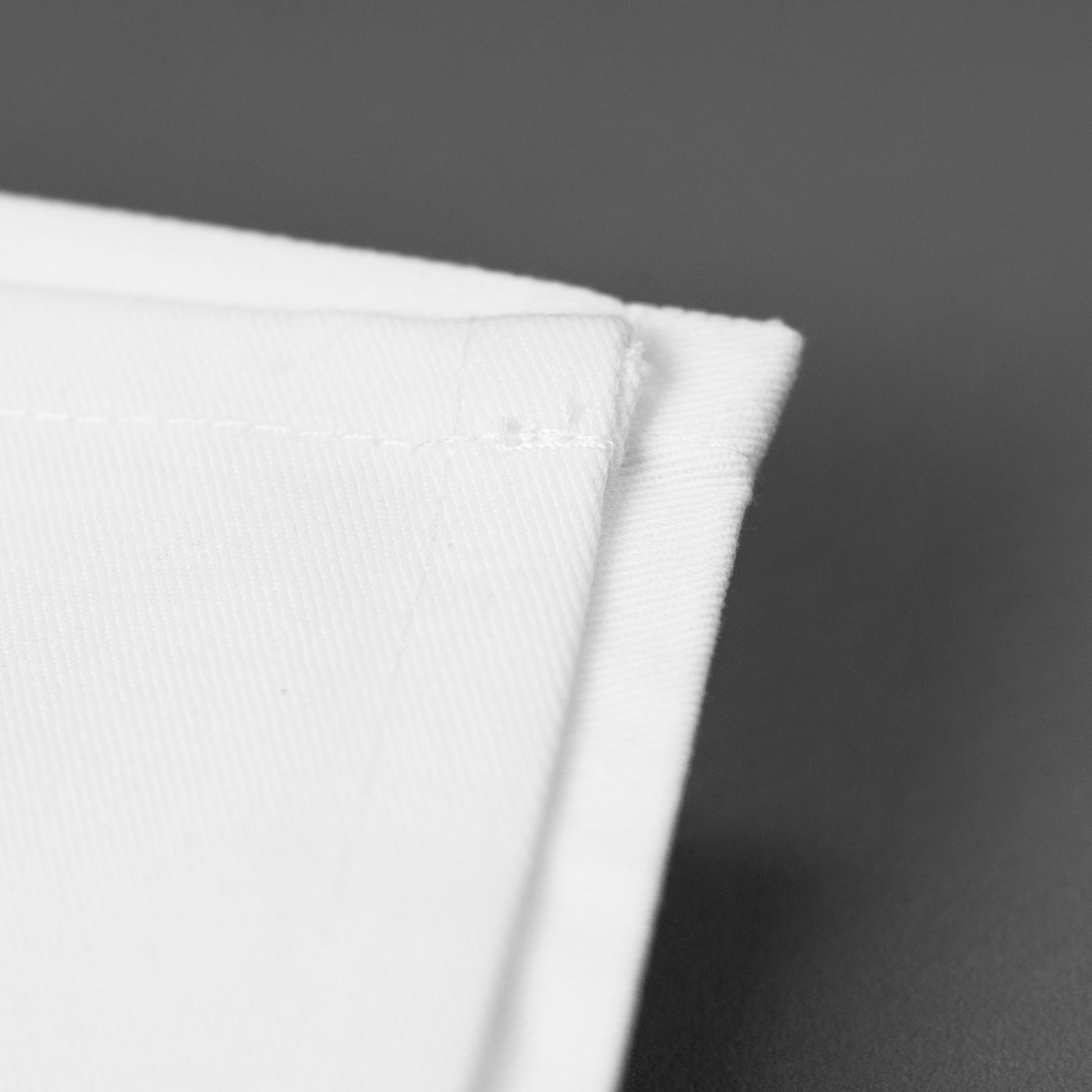 Detailaufnahme einer weißen Baumwollserviette mit sauber vernähter Kante