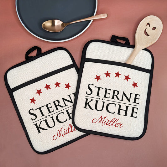 2er-Set Topflappen mit rotem Aufdruck „Sterne Küche“, fünf Sternen und Wunschname unten – frontal dargestellt