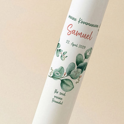 Detailaufnahme der weißen Kommunionkerze mit Eukalyptus-Motiv und Schriftzug „Meine Kommunion“ über dem personalisierten Namen