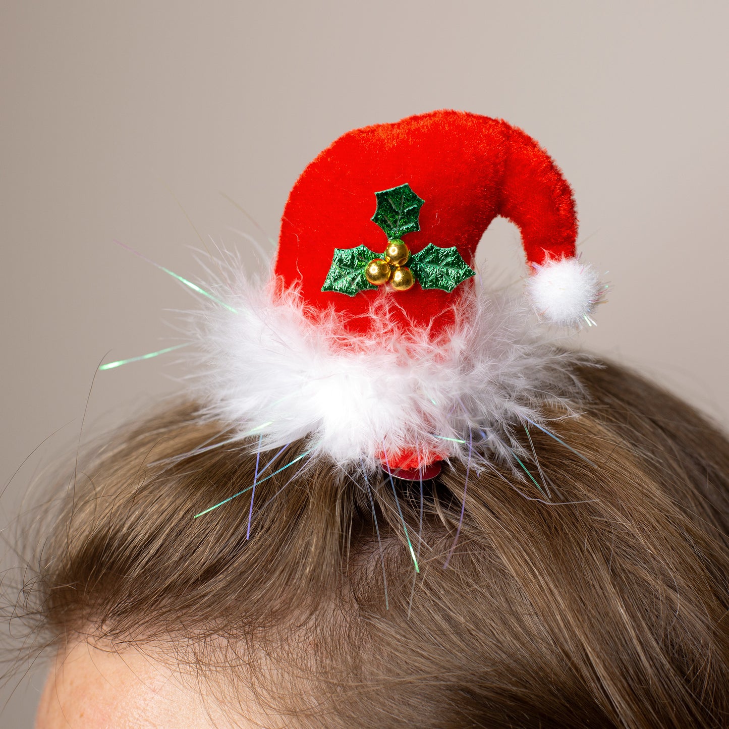 Weihnachtlicher Haarclip in Form einer roten Plüschmütze mit Flaum, getragen im Haar als festliches Accessoire.
