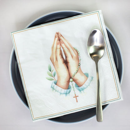 Christliche Serviette mit betenden Händen, Rosenkranz und Kreuz auf einem Teller mit Löffel dekoriert