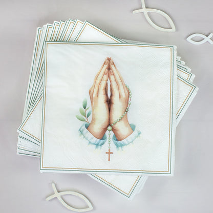 Stapel Servietten mit betenden Händen, Rosenkranz und Kreuz neben christlichen Fischsymbolen