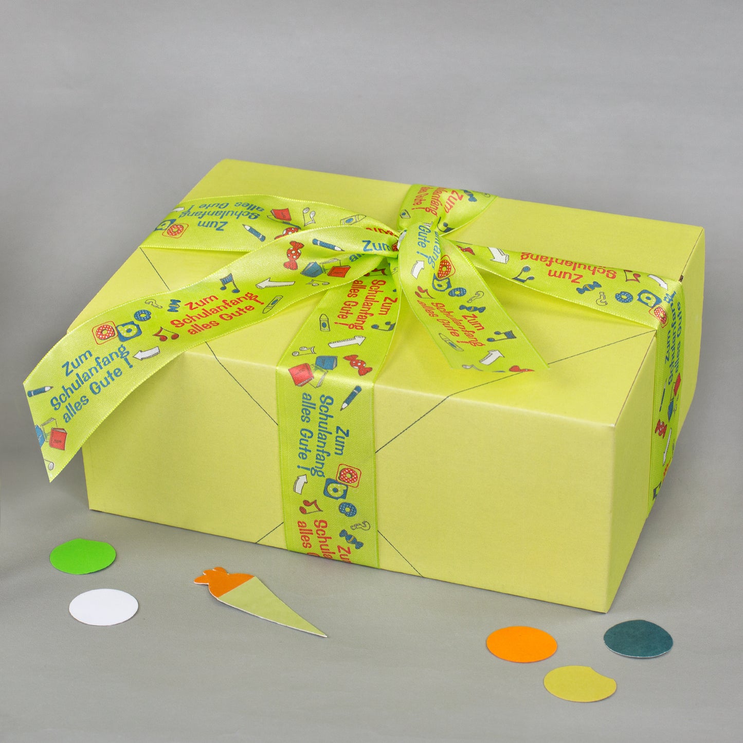 Gelbe Geschenkbox mit dekorativem Geschenkband zur Einschulung und Aufschrift Zum Schulanfang alles Gute