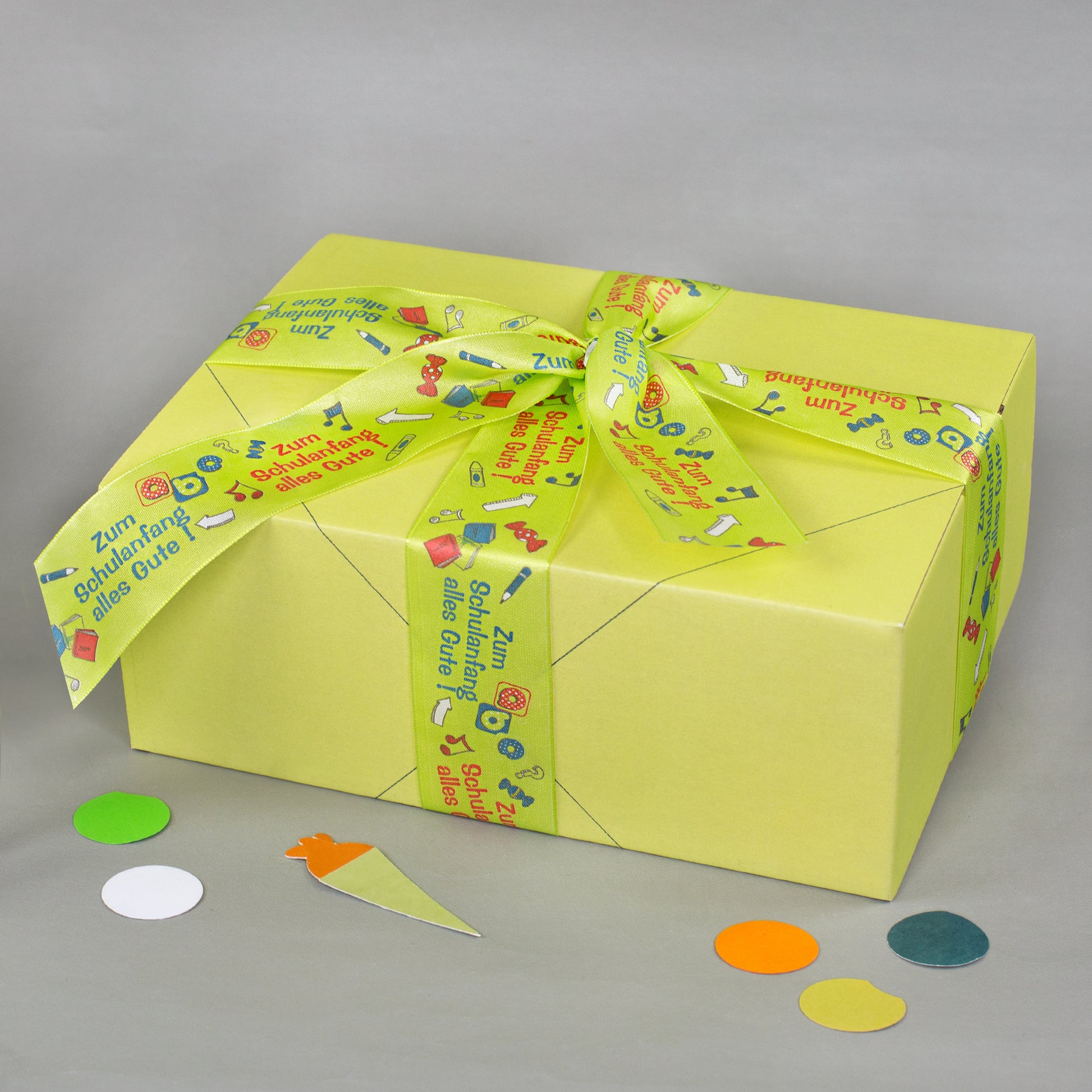 Gelbe Geschenkbox mit dekorativem Geschenkband zur Einschulung und Aufschrift Zum Schulanfang alles Gute