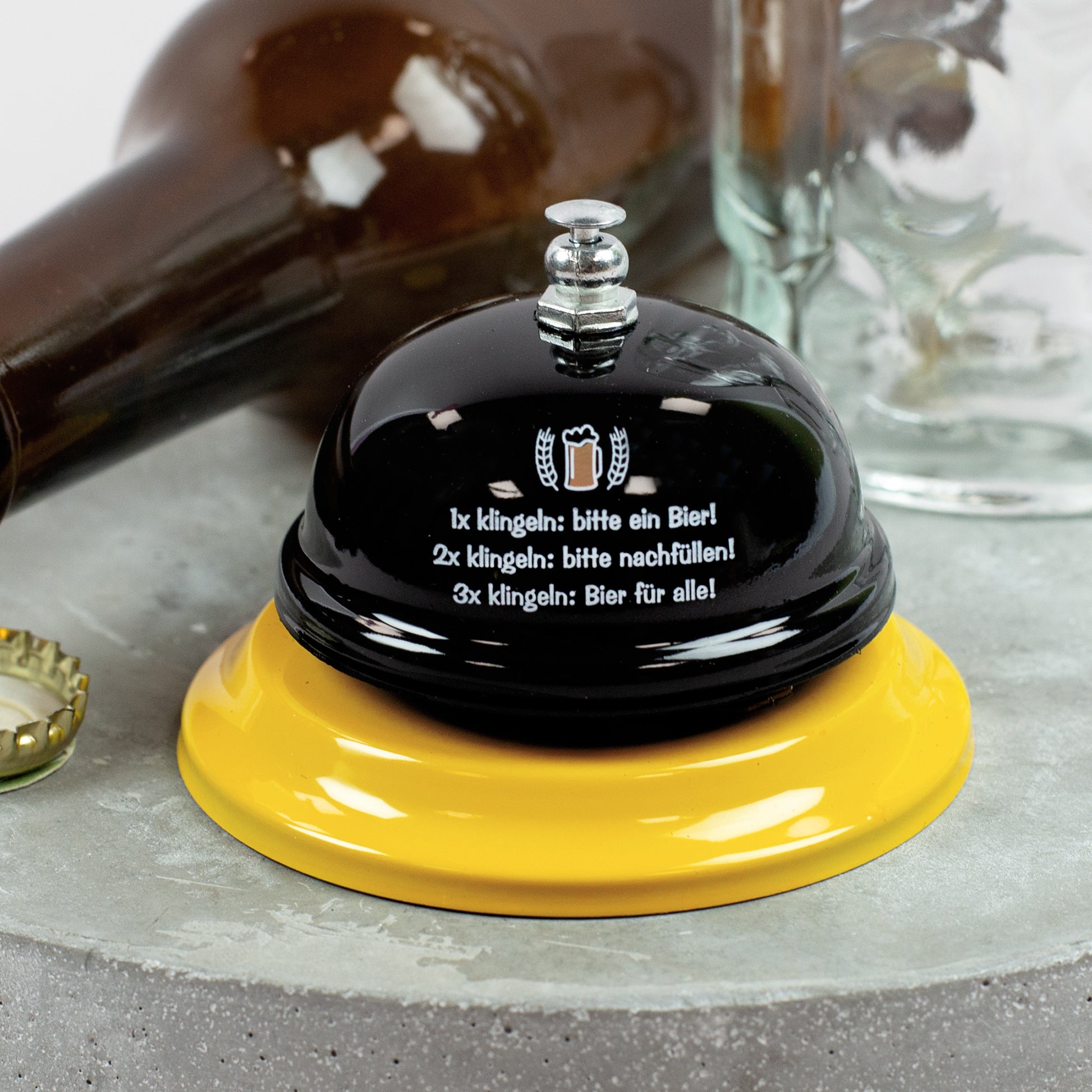 Lustige Bier-Klingel auf Tisch mit Flaschen und Bierkrügen im Hintergrund